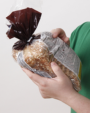 Person holding bag of bread, pointing at nutrition label.